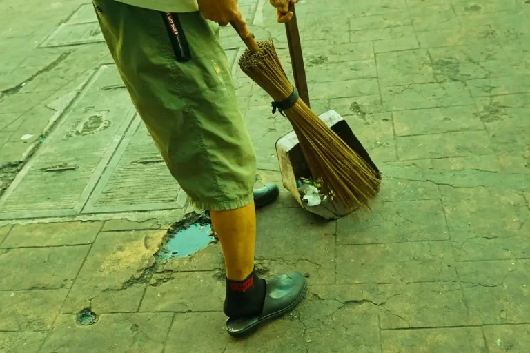 Sense of place shown through daily routine as a street cleaner sweeps a familiar sidewalk