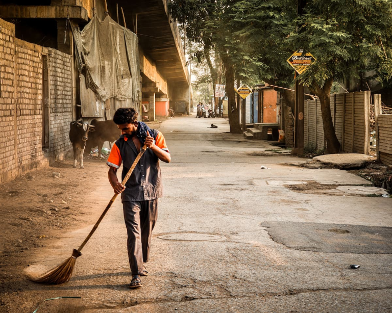 Travel photography tips illustrated through an everyday street scene showing a road sweeper during the early morning in India.